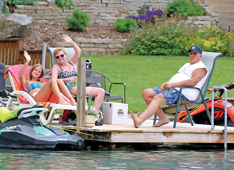 Natalie and Vicky Koss give a wave to the photographer while relaxing on Lime Kiln Lake with Phil Durrant.